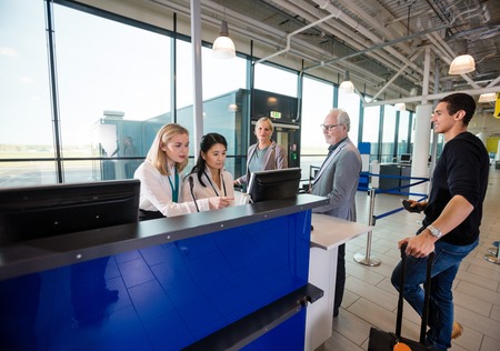 Staff Using Computer While Passengers Waiting In Airportの写真素材