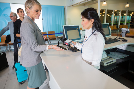 Airport Receptionist Scanning Barcode On Smart Phone Held By Busの写真素材