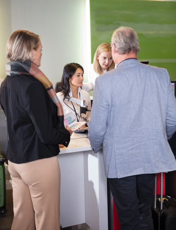Staff Assisting Senior Passengers At Airport Check-in Deskの写真素材
