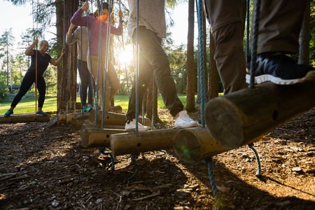 Business People Crossing Swinging Logs In Forestの写真素材