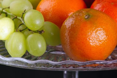 closeup shot of a satsumas and grapes on a glass plateの写真素材