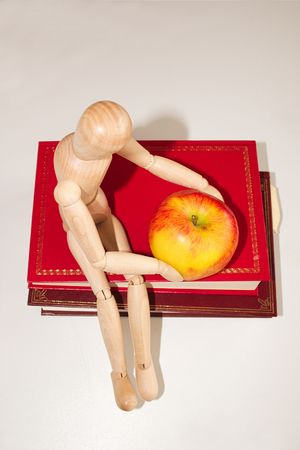 mannequin sitting on top of books with a apple for the teacherの写真素材