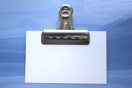 note in a bullclip against a blue backgroundの写真素材