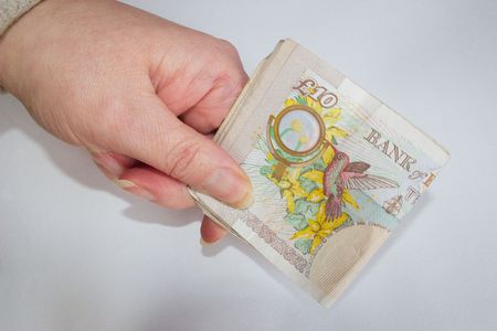holding folded ten pound notesの写真素材