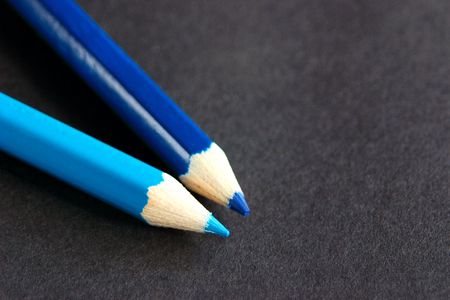 two blue crayons over a dark backgroundの写真素材