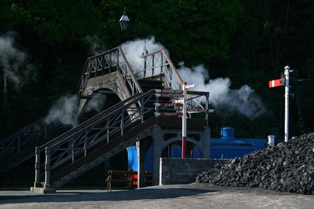 steam engine going under a old iron bridgeの写真素材