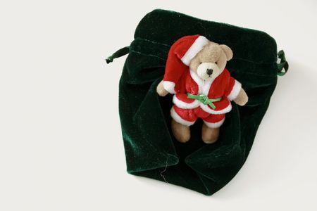 small teddy santa on a plush velvet green purse over a white backgroundの写真素材