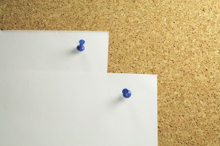 two pieces of white notepaper on a cork board backgroundの写真素材