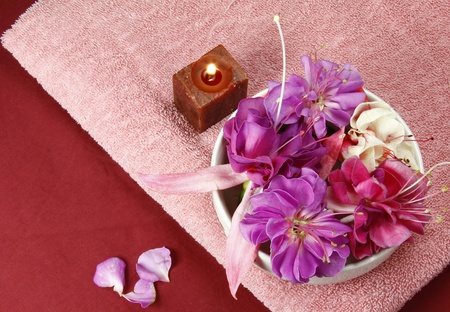 flowers in a bowl with  scented candle and pink towelの写真素材