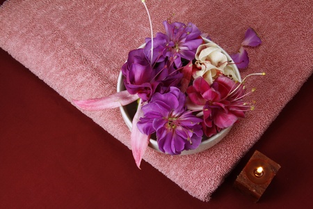 flowers in a bowl with  scented candle and pink towelの写真素材