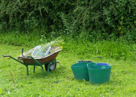 wheelbarrow and trugs with buckets in a garden の写真素材