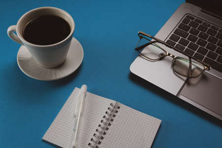 Top view desk with office supplies. Blue background