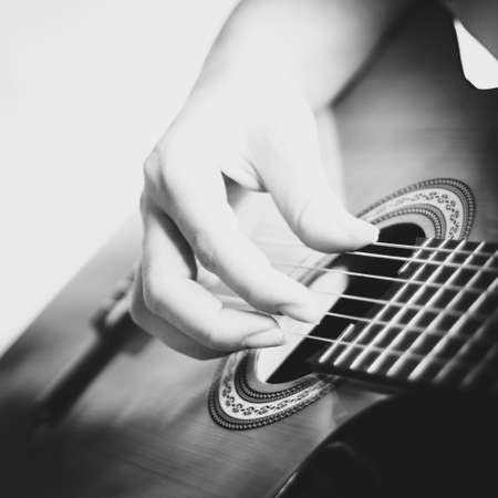 Hand of a woman improvising and playing acoustic guitar. Recreation concept. Black and white...