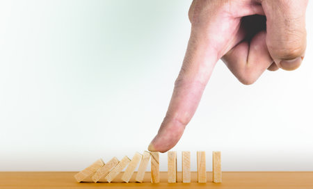 Hand holding the domino effect of the business crisis or the concept of risk protection. Business growthの写真素材