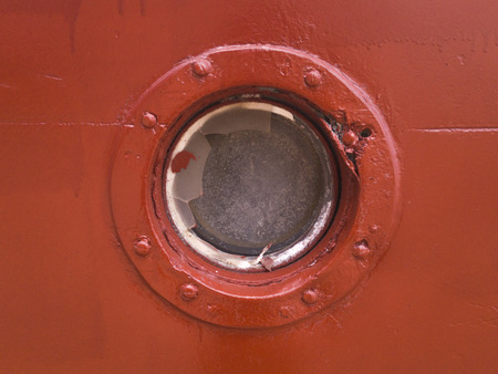 Porthole on the red wall of the old shipの写真素材