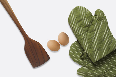 Top View a spatula and green glove and eggs on white backgroundの写真素材