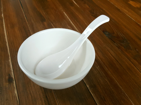 White bowl and spoon ceramic isolated from the vintage wood table textureの写真素材