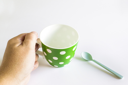 Hand hold green coffee cup with white dots separated from white background.の写真素材