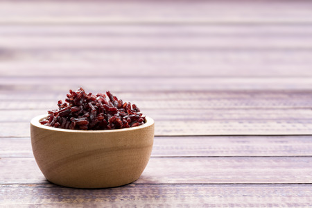 Wooden bowl with brown rice ready to eat. Deep Purple rice, Homnil rice.の写真素材