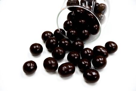 Sweets that are coated with chocolate scattered from clear glass cups. Colorful candies background top view. White background with text areaの写真素材