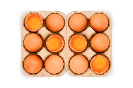 Chicken egg is half broken among other eggs in egg box on white background, top view. With copy areaの写真素材
