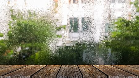The small raindrops on the window glass in the rainy season intersect with the green backdrop. plank table surface. Free place for creativity. Background.の写真素材