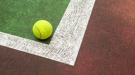 Yellow tennis ball hitting the sidelines on an green and orange artificial tennis court, sport backgroundの写真素材
