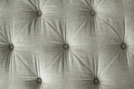 close up grey fabric sofa, texture and background of a grey sofa back with button detail on a thick cloth.の写真素材