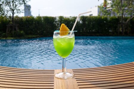 Colourful cocktail on the background of the swimming pool. Healthy beverage in a rustic style. Trendy lifestyle drink.の写真素材