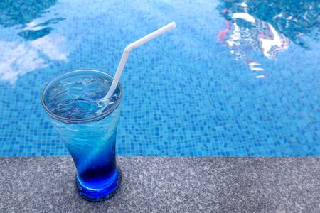 Colourful cocktail on the background of the swimming pool. Healthy beverage in a rustic style. Trendy lifestyle drink.の写真素材