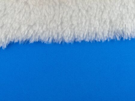 Artificial white fur laid on a blue sponge surface for backgroundの写真素材