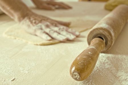 Woman hands work into dough pizza