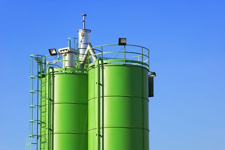 Two green silos agaist blue sky in a construction siteの写真素材