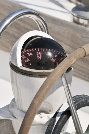 Close-up of a compass and steering wheel on the deck of a sailboatの写真素材