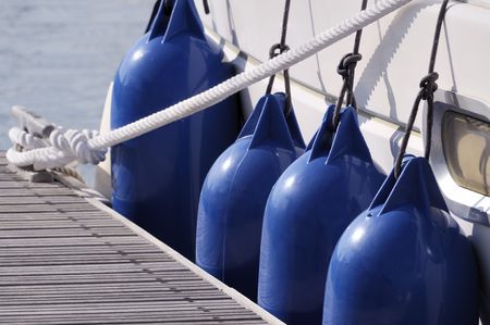 Detail of a boat secured to jetty with a rope and bumpersの写真素材