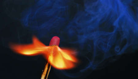 Photo of a burning match with smoke on a black backgroundの写真素材
