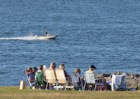 Young man in a motor boat zooms by a group of seniors.のeditorial素材