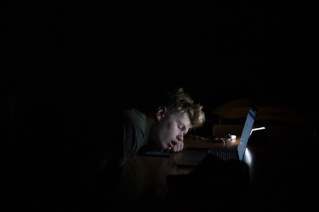 Man sleeps near a laptop at nightの写真素材