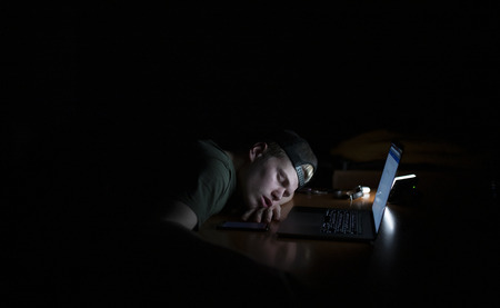 Man sleeps near a laptop at night