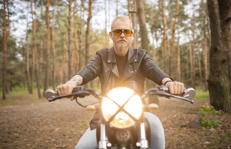 Portrait hipster young guy with a beard and mustache with sunglasses, street casual a motorcycleの写真素材