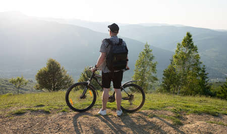 Young guy stands with a bicycle against the background of mountainsの写真素材