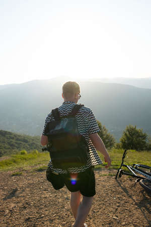 Young guy stands with a bicycle against the background of mountainsの写真素材