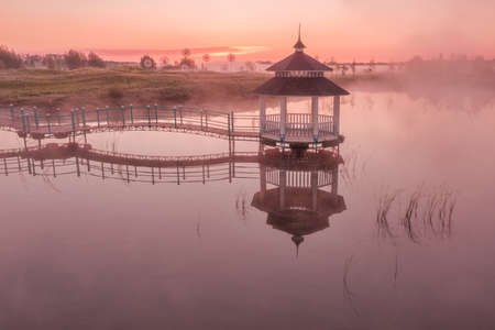 Gazebo on the lake in the park on a foggy summer morning, a great place for relaxing meditation and morning exercises. Vacation, relaxation, nature concept.の写真素材