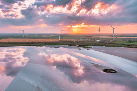 Amazing aerial view of a wind turbine near, a pink lake at sunset, beautiful landscape, juicy...