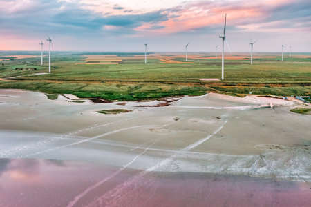 Amazing aerial view of a wind turbine near, a pink lake at sunset, beautiful landscape, juicy multi-colored paintsの写真素材