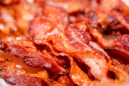 Macro view, of appetizing, tasty, fried, crispy bacon slices, close-up, meat ham to scrambled eggs,...