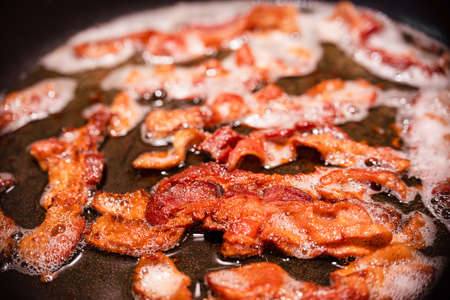 Macro view of appetizing, tasty, bacon slices in a frying pan, close-up, fried meat to scrambled eggs, shallow depth of fieldの写真素材
