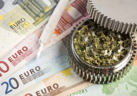 Grinder full of medicinal marijuana and a joing on a backgound of eurosの写真素材