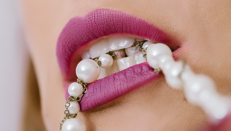 Beautiful mouth with sexy lips biting pearlsの写真素材