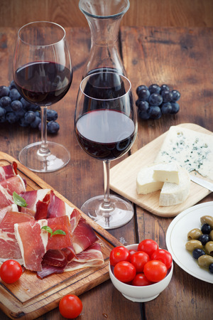sliced prosciutto with red wine and olivesの写真素材